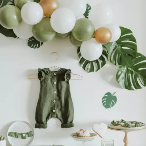 Baby shower decor featuring a green romper, decorative balloons, and tropical leaves, showcasing a festive atmosphere for family celebrations in Pittsburgh.