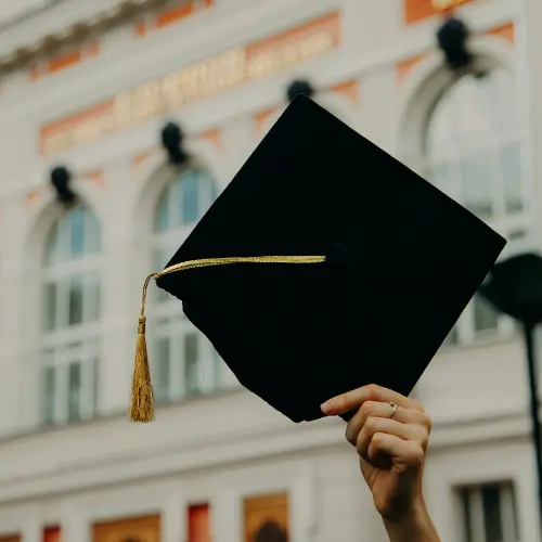 Graduation cap held high in celebration, symbolizing success and achievement, relevant to graduation party catering services in Pittsburgh by Homemade By Colleen.